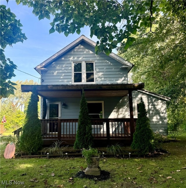 rear view of house featuring a lawn and covered porch