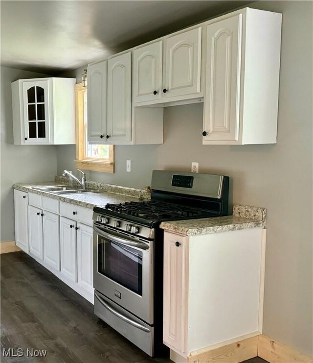 kitchen featuring sink, stainless steel gas range, dark hardwood / wood-style floors, and white cabinetry