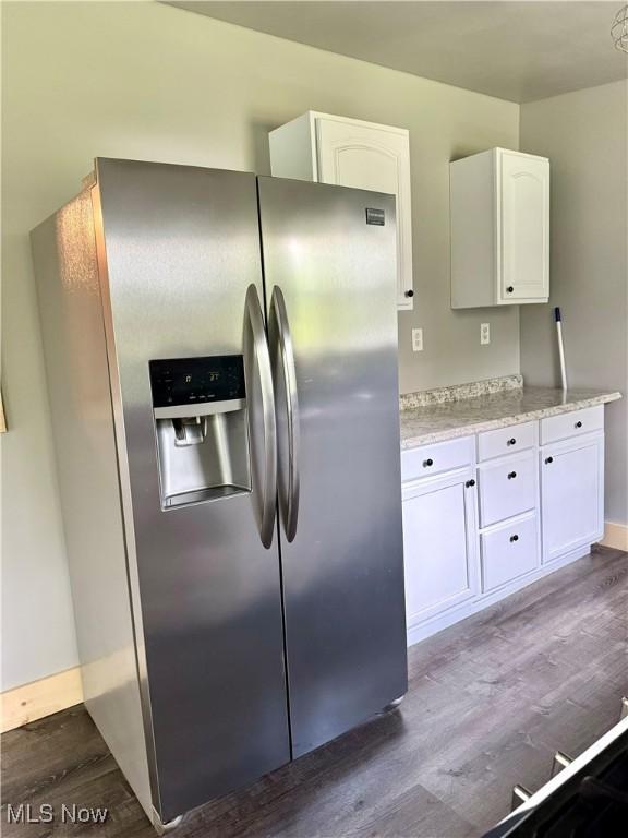 kitchen with dark wood-style floors, white cabinets, stainless steel refrigerator with ice dispenser, and baseboards