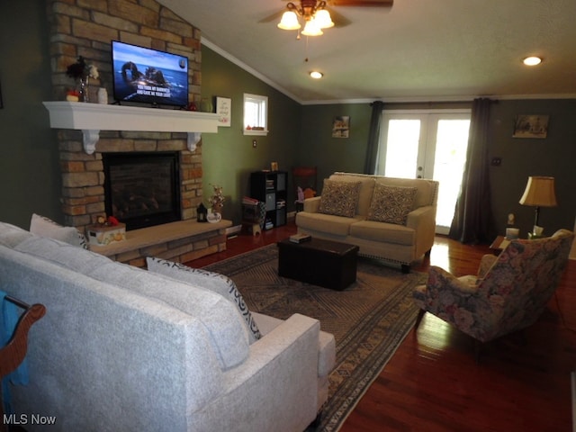 living room with wood-type flooring, vaulted ceiling, a fireplace, ornamental molding, and ceiling fan