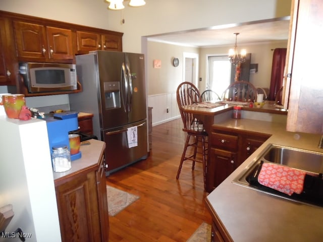 kitchen featuring sink, decorative light fixtures, stainless steel appliances, an inviting chandelier, and dark hardwood / wood-style flooring