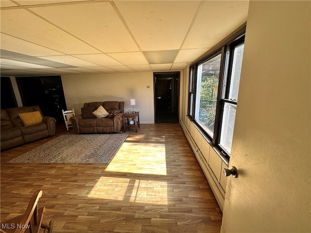 living room featuring a paneled ceiling, hardwood / wood-style floors, and a baseboard radiator