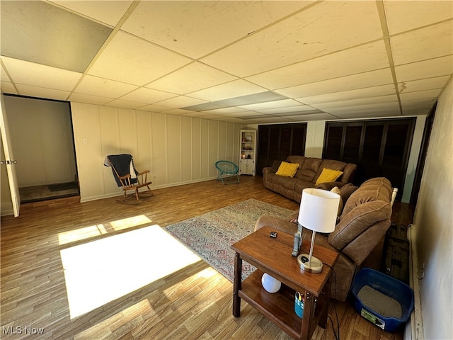 living room featuring a drop ceiling and light hardwood / wood-style flooring