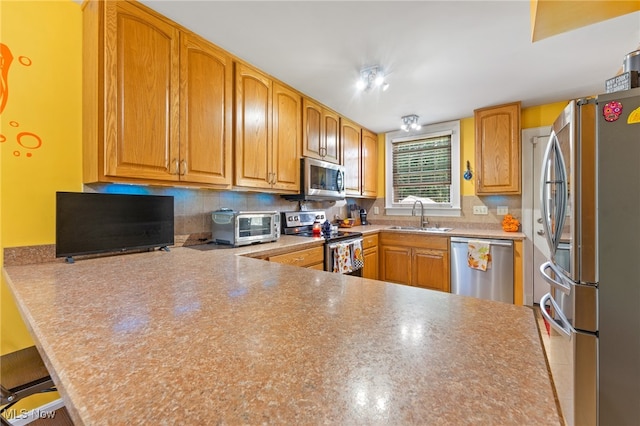 kitchen featuring appliances with stainless steel finishes, backsplash, kitchen peninsula, and sink