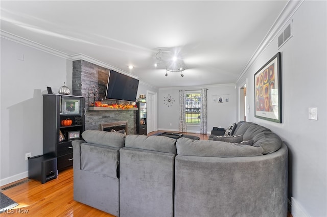 living room with crown molding, a stone fireplace, and hardwood / wood-style flooring