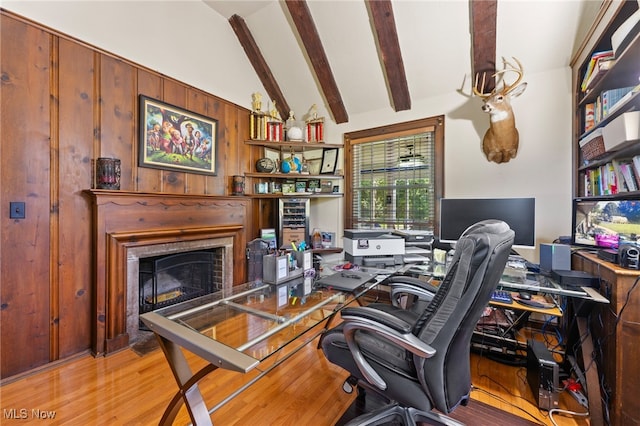 office with wooden walls, vaulted ceiling with beams, and light hardwood / wood-style floors