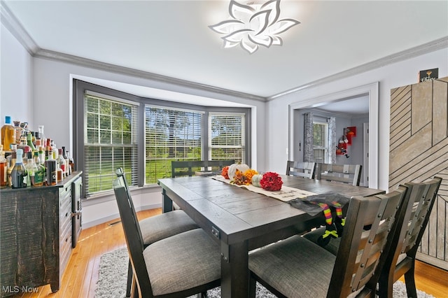 dining area with light wood-type flooring, ornamental molding, and a healthy amount of sunlight