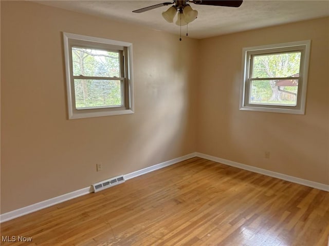 empty room featuring light hardwood / wood-style flooring, ceiling fan, and a healthy amount of sunlight