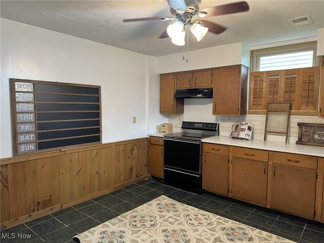 kitchen featuring tasteful backsplash, wooden walls, dark tile patterned flooring, and electric range oven