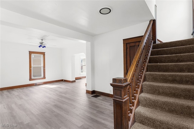 stairs featuring wood-type flooring and ceiling fan