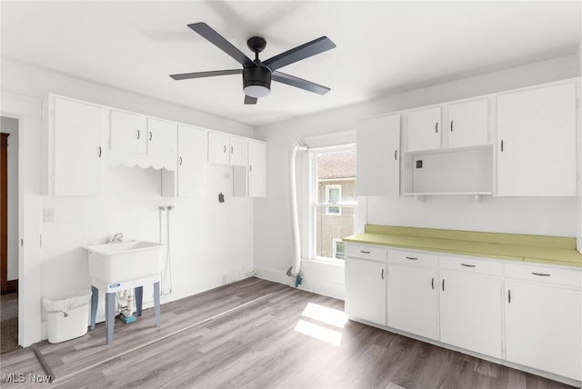 kitchen with ceiling fan, light wood-type flooring, sink, and white cabinetry