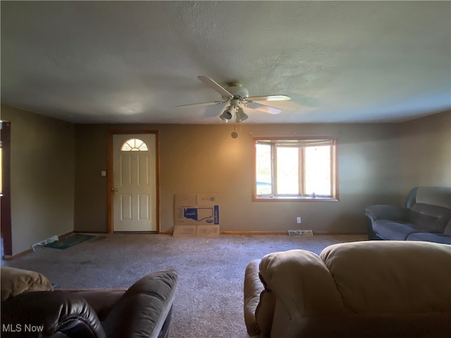 carpeted living room with ceiling fan and a textured ceiling