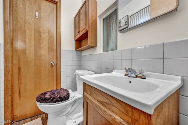 bathroom featuring vanity, tile walls, and toilet