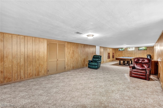 interior space with a textured ceiling, wooden walls, and carpet flooring