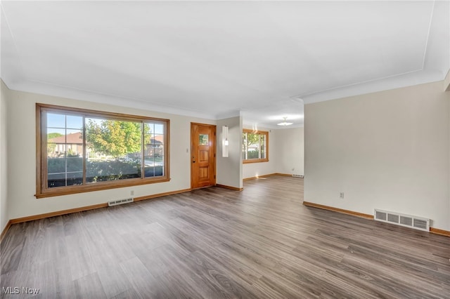 unfurnished living room with wood-type flooring and ornamental molding