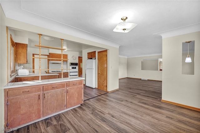 kitchen with hanging light fixtures, decorative backsplash, white appliances, and dark wood-type flooring