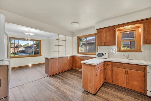 kitchen featuring white appliances, a healthy amount of sunlight, kitchen peninsula, and light hardwood / wood-style flooring