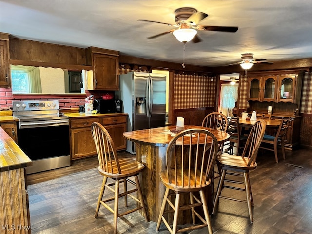 kitchen featuring dark hardwood / wood-style floors, tasteful backsplash, wood walls, butcher block counters, and appliances with stainless steel finishes