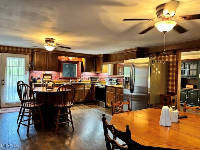 kitchen with appliances with stainless steel finishes, tasteful backsplash, a kitchen bar, ceiling fan, and dark hardwood / wood-style floors