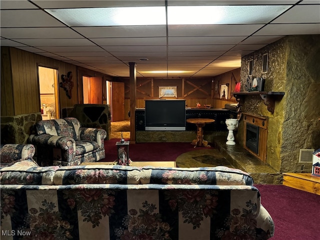 living room featuring a drop ceiling and wood walls