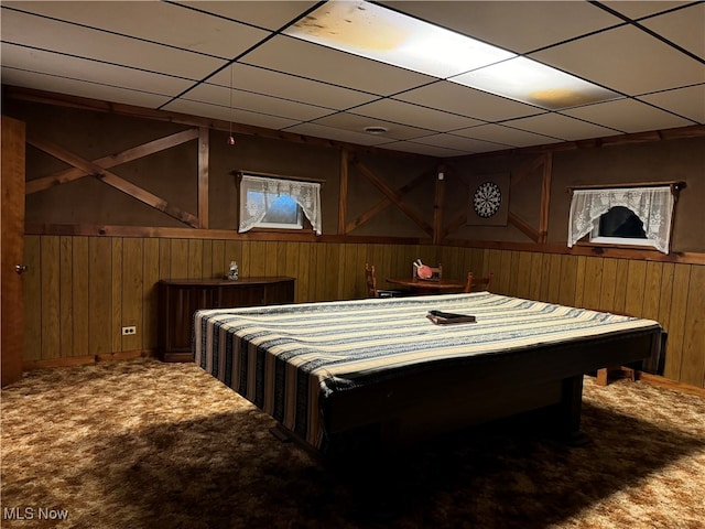 playroom with wooden walls, a drop ceiling, and carpet flooring