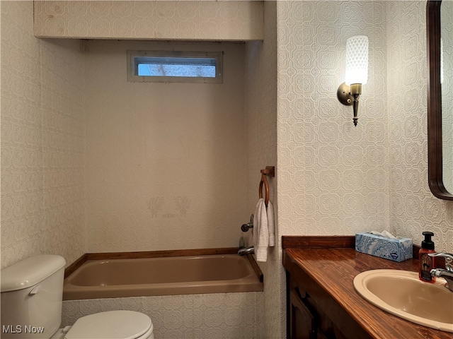 bathroom featuring toilet, vanity, and a washtub