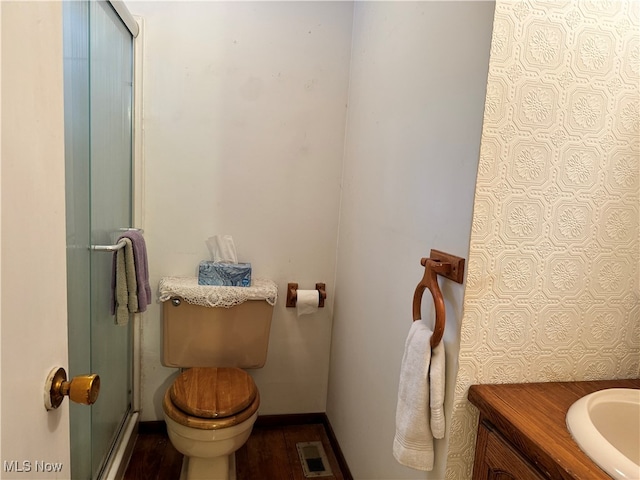 bathroom with wood-type flooring, vanity, toilet, and a shower with door