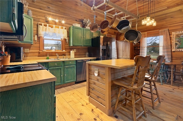 kitchen featuring wooden walls, green cabinetry, light hardwood / wood-style flooring, and stainless steel appliances