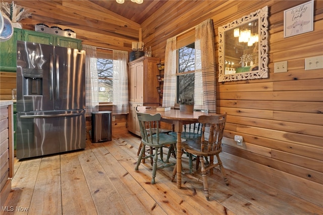 dining space featuring lofted ceiling, wood walls, wood ceiling, and light hardwood / wood-style flooring