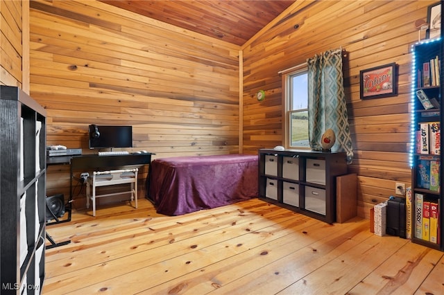 bedroom featuring wooden walls, lofted ceiling, and light hardwood / wood-style floors