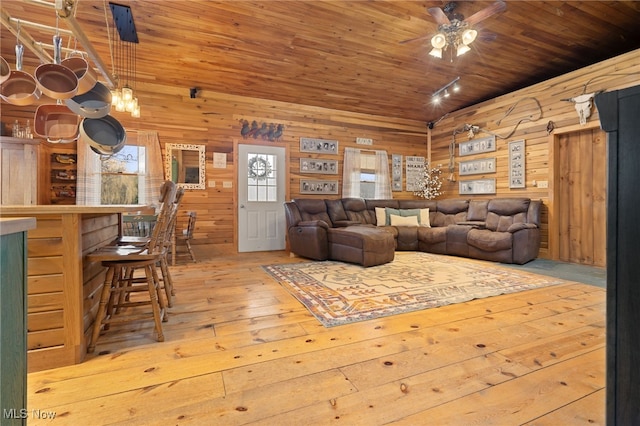 living room with light wood-type flooring, wood ceiling, wood walls, and ceiling fan