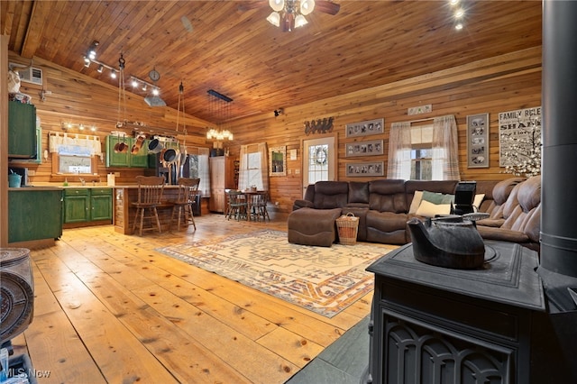 living room featuring high vaulted ceiling, wood walls, a wood stove, wooden ceiling, and light hardwood / wood-style flooring