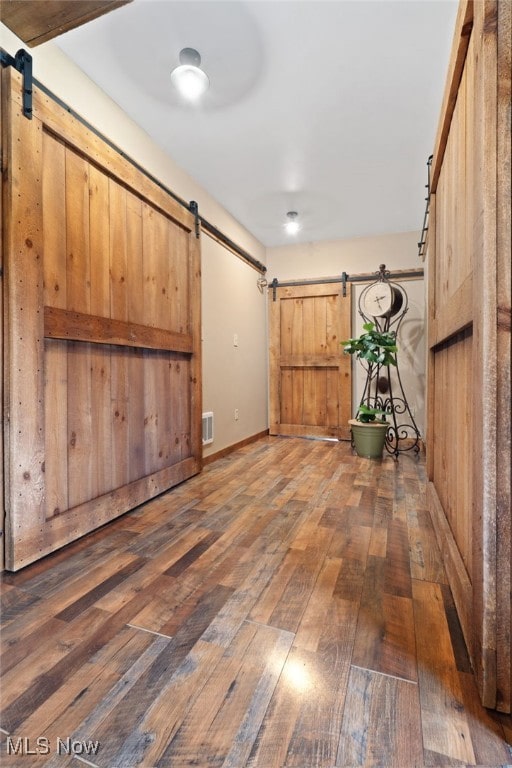 interior space with a barn door and dark wood-type flooring