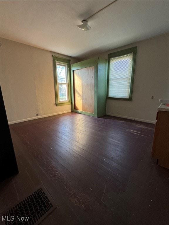 spare room featuring track lighting and dark hardwood / wood-style flooring