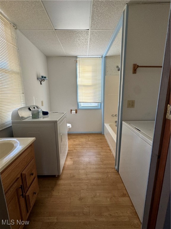 full bathroom with separate washer and dryer, a drop ceiling, wood-type flooring, vanity, and toilet