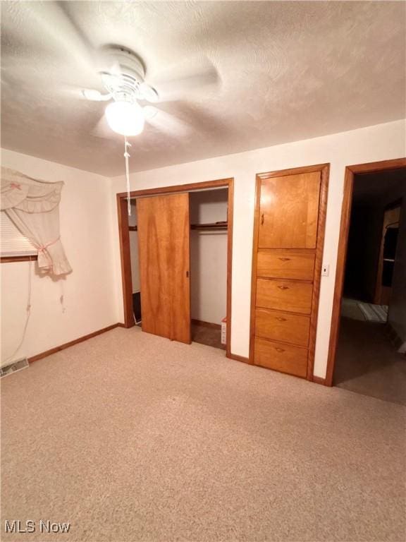 unfurnished bedroom featuring ceiling fan, a textured ceiling, and light carpet