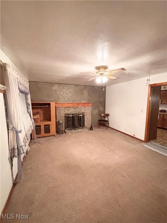 unfurnished living room featuring ceiling fan, carpet, a textured ceiling, and a fireplace