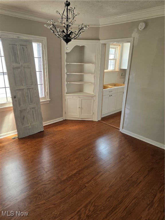 unfurnished dining area featuring a textured ceiling, dark hardwood / wood-style flooring, a chandelier, and a wealth of natural light