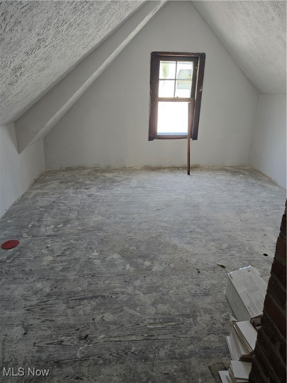 additional living space with a textured ceiling and vaulted ceiling