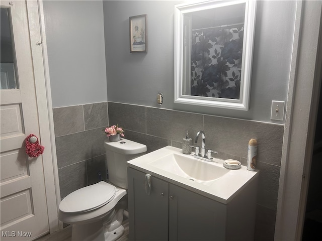 bathroom with tile walls, vanity, and toilet