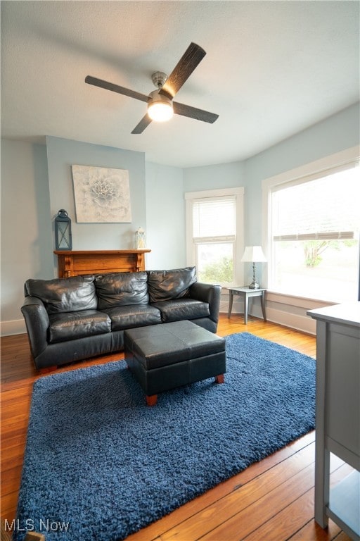 living room featuring wood-type flooring, ceiling fan, and a fireplace