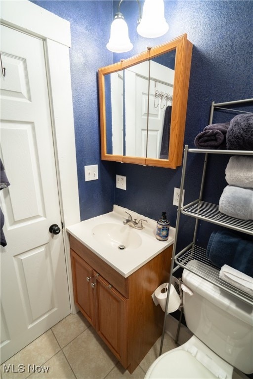 bathroom with tile patterned flooring, vanity, and toilet