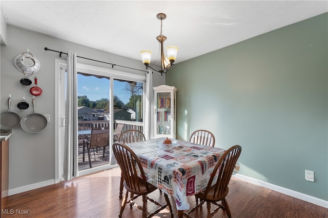 dining room featuring a notable chandelier, wood-type flooring, and a textured ceiling