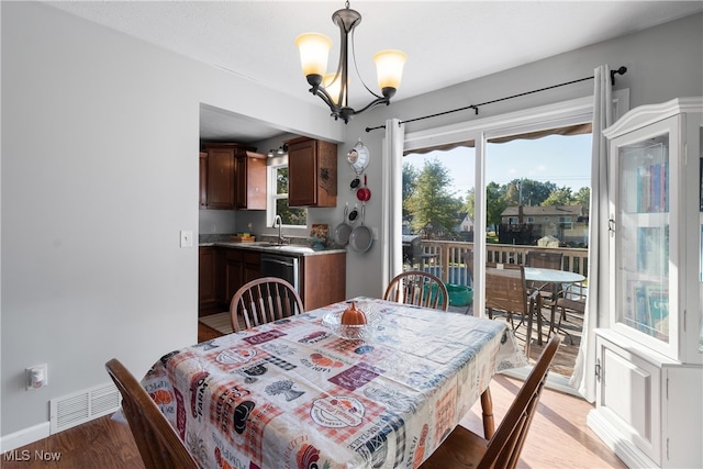 dining space featuring an inviting chandelier, light hardwood / wood-style floors, and sink