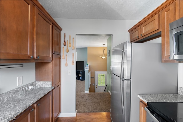 kitchen with light wood-type flooring, a textured ceiling, light stone countertops, and electric range