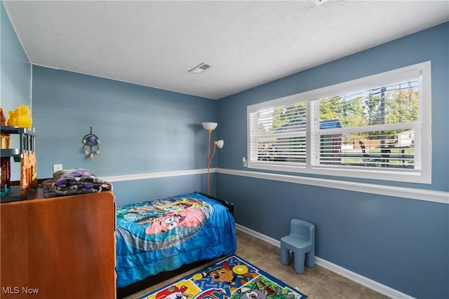 bedroom with a textured ceiling and light tile patterned floors