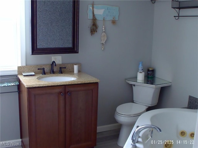 bathroom with vanity, a tub to relax in, and toilet