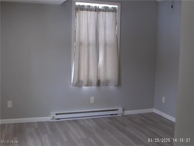 unfurnished room featuring hardwood / wood-style flooring and a baseboard radiator