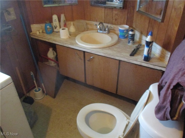 bathroom with vanity, wood walls, and toilet