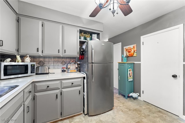 kitchen featuring appliances with stainless steel finishes, gray cabinetry, ceiling fan, and tasteful backsplash